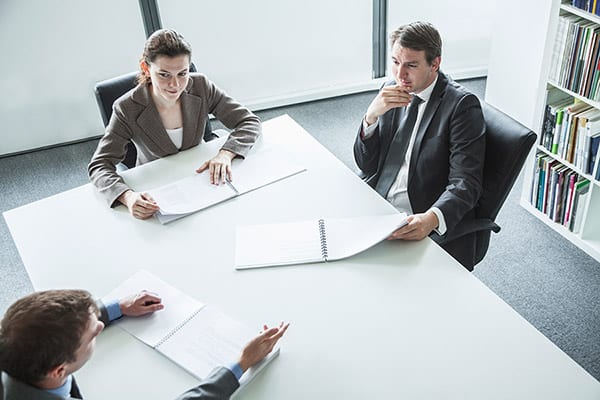tres personas en una mesa de reunion